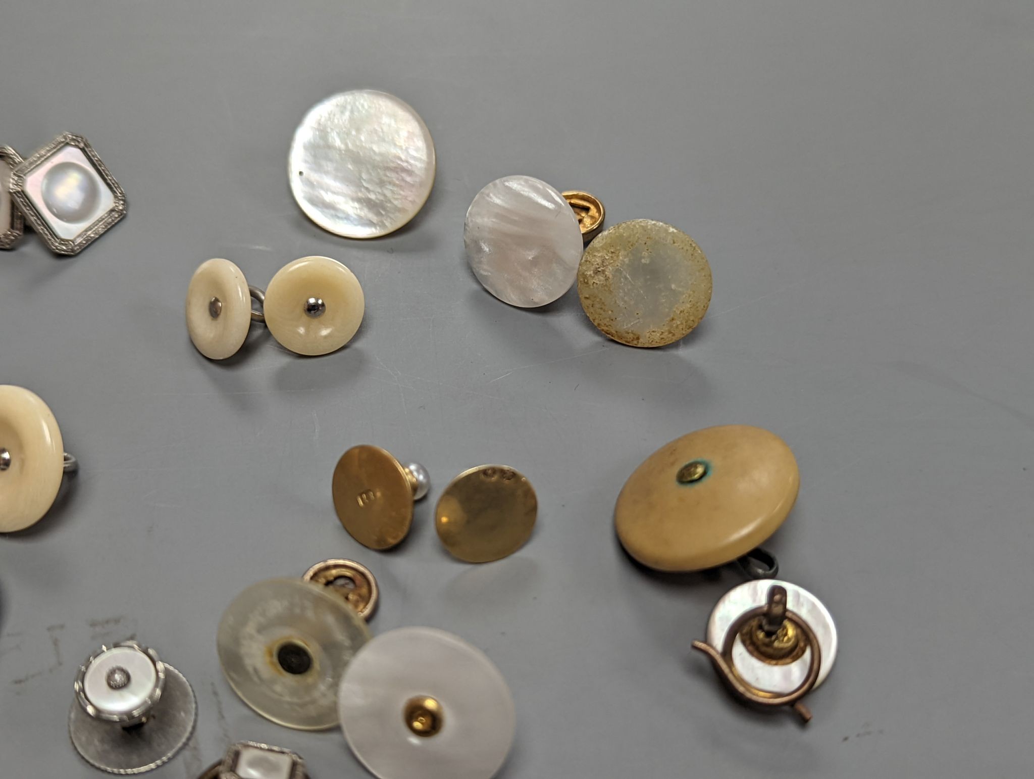 Two pairs of 18ct and mother of pearl cufflinks, one set with sapphires, both with gilt metal associated links, together with a quantity of base metal buttons, cufflinks, studs, etc.